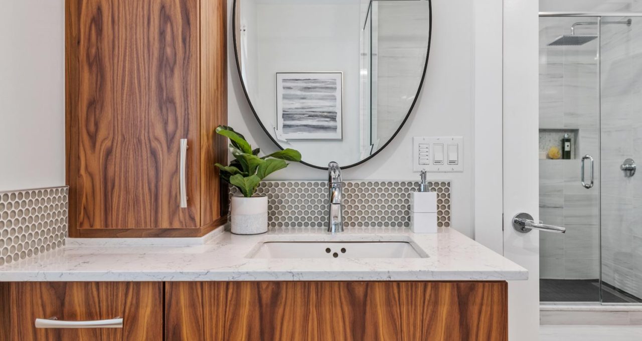 Walnut vanity with round mirror and mosaic backsplash