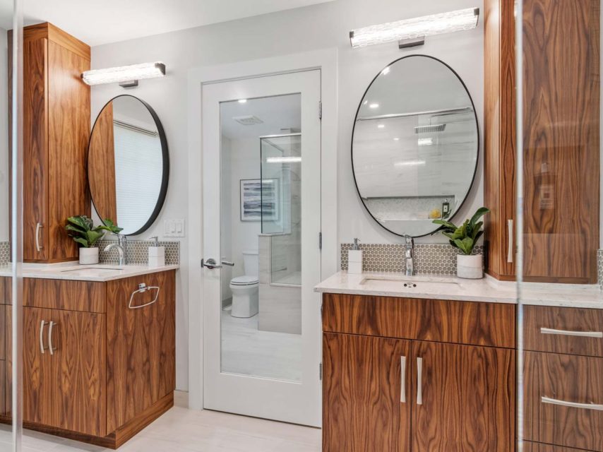 Walnut bathroom with round mirrors and pass-through